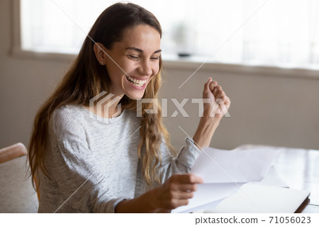 Excited young lady reading postal letter of loan request approval Excited young lady reading postal letter of loan request approval 71056023