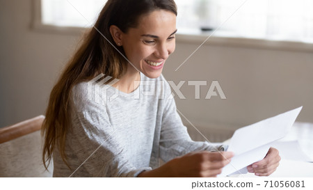 Smiling millennial woman is glad reading letter from beloved person 71056081