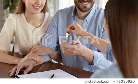 Realtor giving keys of new house to happy millennial family Realtor giving keys of new house to happy millennial family 71056920