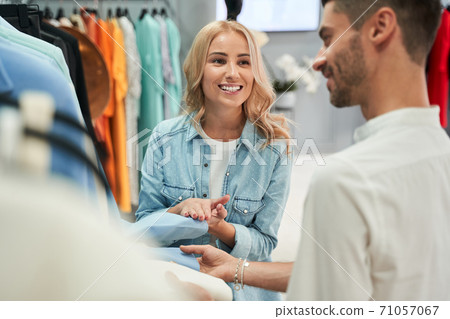 Assistant helping to choose clothes to his customer Assistant helping to choose clothes to his customer 71057067