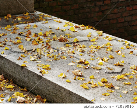 Granite stone with emossed cross covered with yellow lime tree leave 71059010