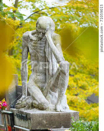 Skinny old man, male statue sitting on a tombstone. Skinny old man, male statue sitting on a tombstone. 71059015