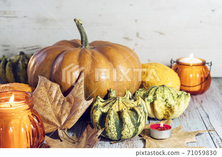 Thanksgiving background, composition with pumpkins, dry autumn leaves, candles on wooden background. Thanksgiving background, composition with pumpkins, dry autumn leaves, candles on wooden background. 71059830