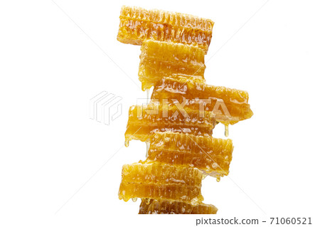Drops of fresh honey dripping from a pyramid of wax honey. vitamin nutrition and bee product. 71060521