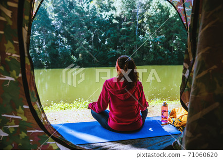 Young woman in the sport wear outfit is sitting and relaxing in the camping in the forest. Young woman in the sport wear outfit is sitting and relaxing in the camping in the forest. 71060620
