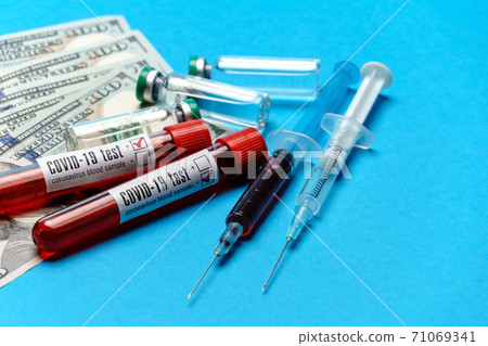 Close up 100 US dollar bills, vaccine ampoules and blood sample in test tube over blue background 71069341