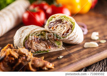 Cut tortilla wrap filled with kebab meat and vegetables Cut tortilla wrap filled with kebab meat and vegetables 71069502
