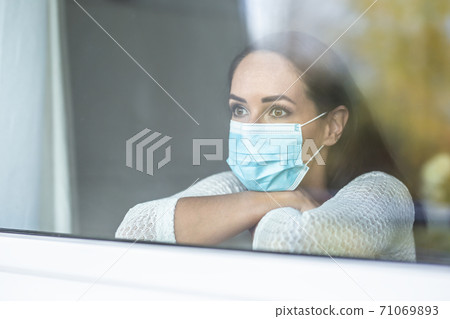 Covid-19 pandemic depression caused by social isolation during a quarantine by a face mask wearing female Covid-19 pandemic depression caused by social isolation during a quarantine by a face mask wearing female 71069893
