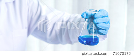 Scientists hold a glass tube filled with blue chemical liquid for research and analysis in a laboratory 71070173
