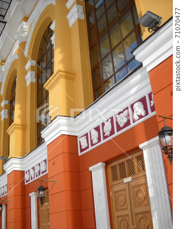 The facade of the building of the Drama Theater. Pilasters are painted white. Walls freshly painted in yellow and orange. Satyr masks,tall glass windows distinguish the exterior of the cultural center 71070477