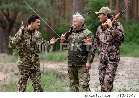 Happy Hunters in Forest Walking with Shotguns. 71071543