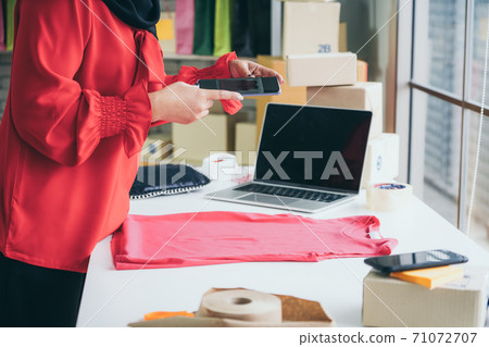 Online seller works at home office and packs shipping delivery box to customer. Online seller works at home office and packs shipping delivery box to customer. 71072707