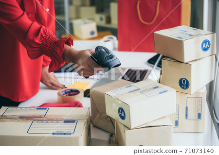 Online seller works at home office and packs shipping delivery box to customer. Online seller works at home office and packs shipping delivery box to customer. 71073140
