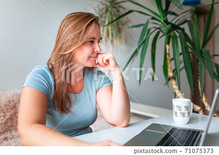 Middle age woman sitting at the table at home working using computer laptop. Work from home during coronovirus pandemic concept Middle age woman sitting at the table at home working using computer laptop. Work from home during coronovirus pandemic concept 71075373