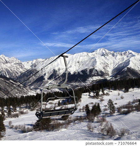 Chair-lift at ski resort and snowy winter mountains at nice sun day Chair-lift at ski resort and snowy winter mountains at nice sun day 71076664