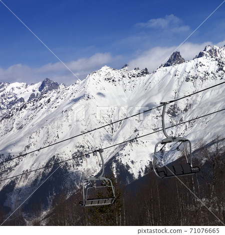 Ski resort with chair lift and snow mountains at nice sunny day Ski resort with chair lift and snow mountains at nice sunny day 71076665
