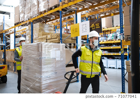 Group of workers with face mask working indoors in warehouse, coronavirus concept. Group of workers with face mask working indoors in warehouse, coronavirus concept. 71077041