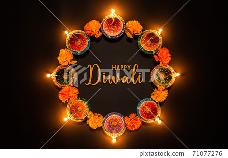 Happy Diwali - Clay Diya lamps lit during Dipavali, Hindu festival of lights celebration. Colorful traditional oil lamp diya on black background 71077276