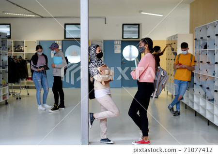 Young students friends with face masks back at college or university, coronavirus concept. 71077412