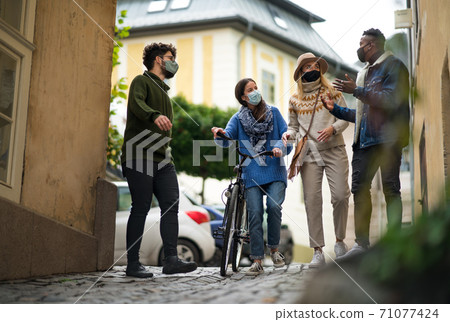 Group of young people with bicycle outdoors in town, walking. Coronavirus concept. Group of young people with bicycle outdoors in town, walking. Coronavirus concept. 71077424