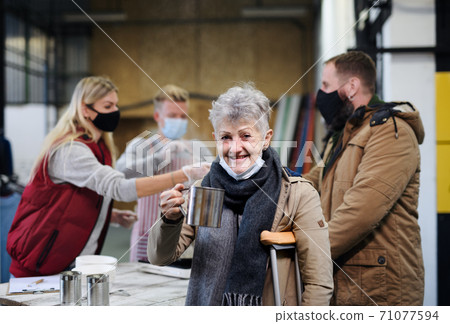 Volunteers serving hot soup for homeless in community charity donation center, coronavirus concept. 71077594