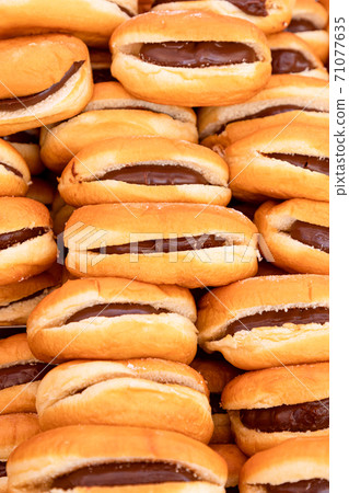 Freshly baked buns with chocolate or nougat cream filling in Italian sunday food market 71077635