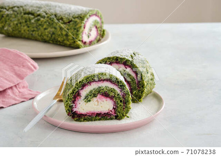 Green spinach roll cake with cream cheese and raspberries filling on plate. Restaurant, bakery menu or recipe concept. Copy space. Christmas and new year dessert. 71078238