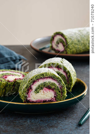 Green spinach roll cake with cream cheese and raspberries filling on plate. Restaurant, bakery menu or recipe concept. Copy space. Christmas and new year dessert. 71078240