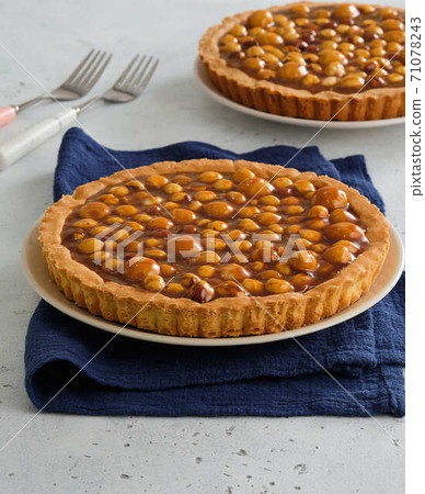 Pie with hazelnuts and macadamia nuts. Nut tart with caramel. 71078243