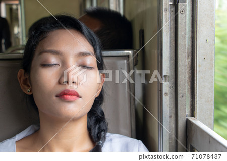 Portrait of young woman sleeping in the train. Passenger sleep in the old wagon of a train. 71078487