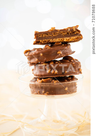 Chocolate biscuit sandwich in chocolate and nut glaze on christmas background Chocolate biscuit sandwich in chocolate and nut glaze on christmas background 71078688