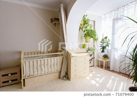 A newborn baby's crib and a changing table stand at the entrance to the glazed balcony A newborn baby's crib and a changing table stand at the entrance to the glazed balcony 71079400