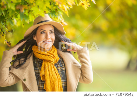 Fashionable female model wears hat, jacket and scarf on a fall day outdoors 71079542