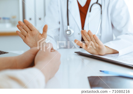 Unknown woman-doctor and patient discussing something while sitting at the table in clinic, close-up. Medicine concept 71080216