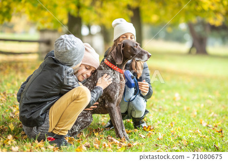 Children petting a dog outdoors during a fall walk in the nature Children petting a dog outdoors during a fall walk in the nature 71080675