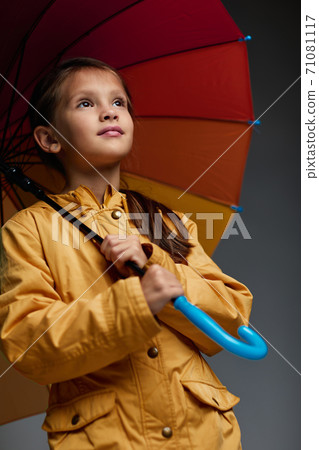 Cheerful child girl with umbrella on gray background. 71081117