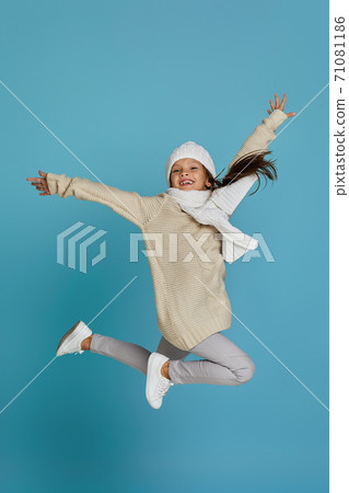little child girl in winter knitted hat and sweater jumping 71081186