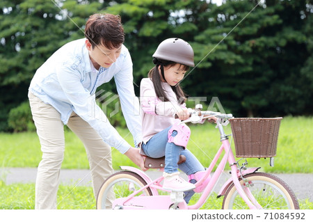 Parents and children practicing by taking training wheels on their bicycles 71084592