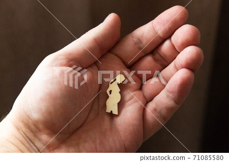Silhouette figure of a pregnant woman lies on a man's hand 71085580