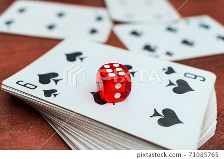 Red dice lie on a deck of playing cards in a casino. Casino gambling with dice and cards Red dice lie on a deck of playing cards in a casino. Casino gambling with dice and cards 71085765