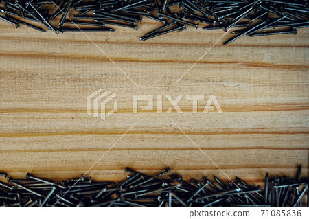 Small nails are scattered on the wooden Board. Background with space to copy. 71085836