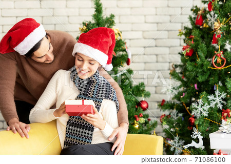Merry Christmas. Boyfriend surprising his girlfriend with Christmas gift. 71086100
