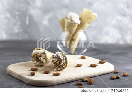 Ice cream background. Fresh ice cream for dessert. Ice cream with almonds on a wooden board. Almond ice cream. Copyspace 71086215