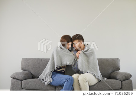 Freezing couple in cool room cuddling in plaid Freezing couple in cool room cuddling in plaid 71086299