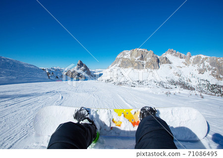 Snowboarder sitting on slope 71086495