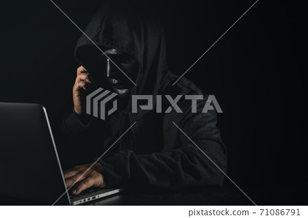 Dangerous anonymous hacker man in hooded and mask using computer and smartphone on black background, breaking into security data corporate server. Internet crime, cyber attack security concept Dangerous anonymous hacker man in hooded and mask using computer and smartphone on black background, breaking into security data corporate server. Internet crime, cyber attack security concept 71086791