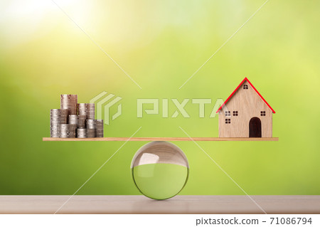 Model house on wooden marble seesaw balancing with stacking coins money on green background. Property investment and home mortgage financial real estate advertising concept Model house on wooden marble seesaw balancing with stacking coins money on green background. Property investment and home mortgage financial real estate advertising concept 71086794