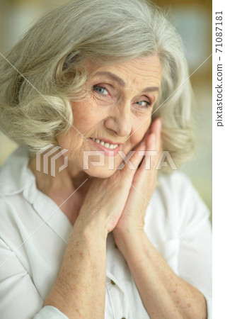 Portrait of beautiful smiling senior woman posing at home 71087181