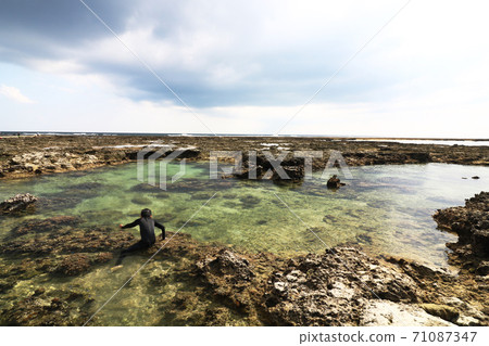 A boy playing with Ino (a small sea made of coral reefs) A boy playing with Ino (a small sea made of coral reefs) 71087347