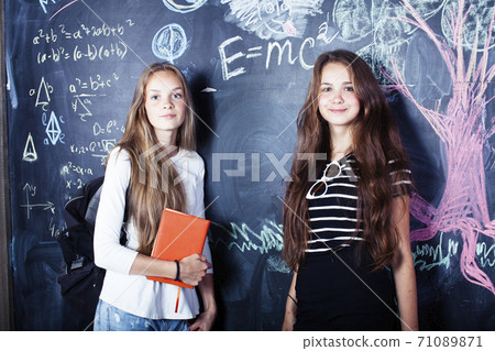back to school after summer vacations, two teen real girls in classroom with blackboard painted together, lifestyle people concept back to school after summer vacations, two teen real girls in classroom with blackboard painted together, lifestyle people concept 71089871